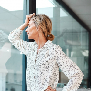 iStock-1273196067_copyright-PeopleImages_square Frau schaut gedankenvoll durch die Glasabtrennung ihres Büros. Copyright: PeopleImages, iStock #1273196067